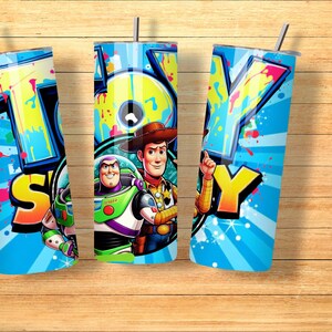 K&ouml;nnte beinhalten: Drei blaue Becher mit dem Wort "TOY" in Graffiti-Schrift. Die Becher zeigen Bilder von Buzz Lightyear und Woody aus Toy Story. Jeder Becher hat einen silbernen Strohhalm.