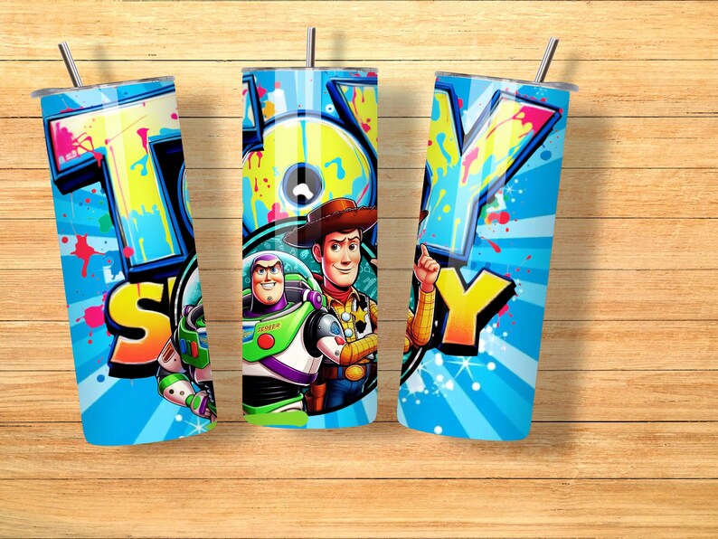K&ouml;nnte beinhalten: Drei blaue Becher mit dem Wort "TOY" in Graffiti-Schrift. Die Becher zeigen Bilder von Buzz Lightyear und Woody aus Toy Story. Jeder Becher hat einen silbernen Strohhalm.