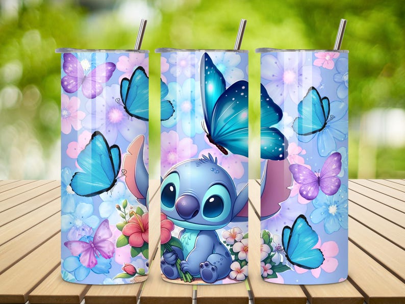 May include: A cylindrical stainless steel tumbler featuring a light blue background with a pattern of pink and blue flowers, purple and blue butterflies, and a blue cartoon character holding a pink flower, topped with a thin metal straw.