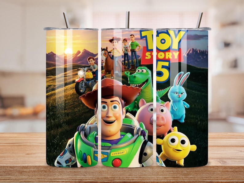 May include: A cylindrical metal tumbler with a straw featuring a colorful Toy Story 5 graphic print. The design displays characters including Woody, Buzz Lightyear, Rex, Hamm, Ducky, Bunny, and others set against a sunset landscape with mountains.