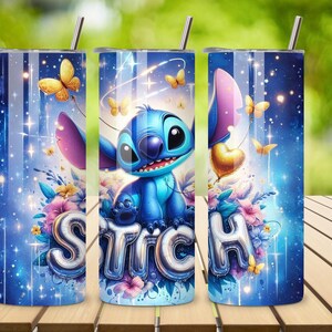 May include: A blue tumbler featuring the character Stitch, surrounded by butterflies, flowers, and the word "STITCH" in silver balloon letters. The design includes a starry background and a silver straw.