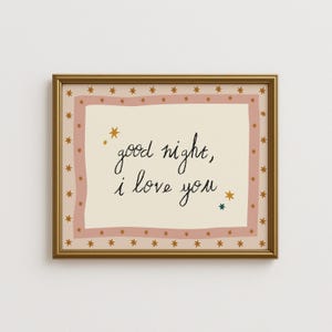 Könnte beinhalten: Ein gerahmter Druck mit den Worten "good night, I love you" in schwarzer Schrift. Der Druck hat einen cremefarbenen Hintergrund mit einem rosa Rand und goldenen Sternen. Der Rahmen ist goldfarben.