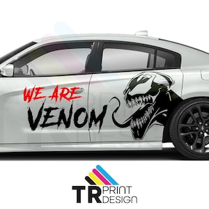May include: A white car with a black and red graphic design. The design features the words "WE ARE VENOM" and a black and white illustration of Venom's face. The car has black wheels.