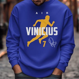 A man wearing a blue sweatshirt with a yellow graphic and text printed on it.