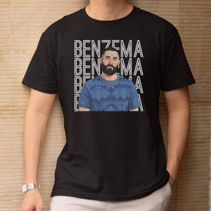 A black t-shirt with a graphic design featuring a man with a beard wearing a blue shirt.