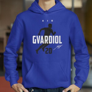 A person wearing a blue hoodie with a graphic design featuring a silhouette of a person running and the text "AIR GVARDIOL 20".