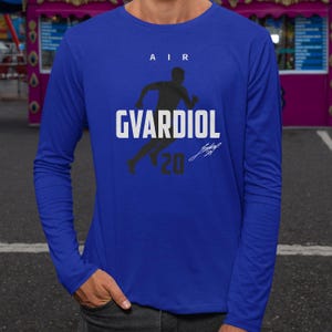 A person wearing a blue long-sleeved shirt with a graphic design featuring a running figure and the text "AIR GVARDIOL 20".