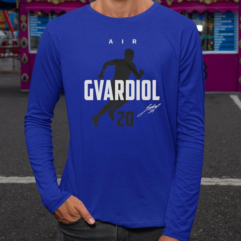 A person wearing a blue long-sleeved shirt with a graphic design featuring a running figure and the text "AIR GVARDIOL 20".