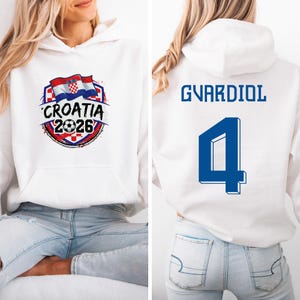 A white hoodie with a graphic design and text, and a number on the back.