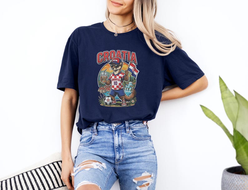 A woman wearing a navy blue t-shirt with a graphic of a cartoon character and the word "Croatia" printed on it, standing against a white wall.