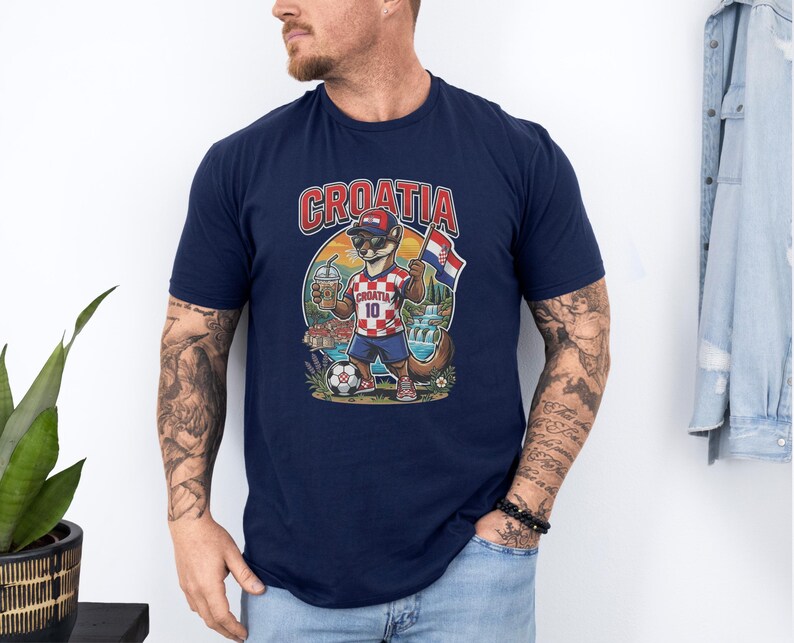 A man wearing a navy blue t-shirt with a graphic of a cat playing soccer and the word "Croatia" printed on it.