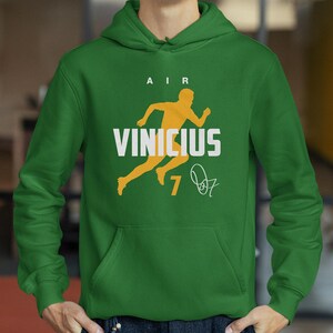 A person wearing a green hoodie with a yellow graphic and text printed on it.