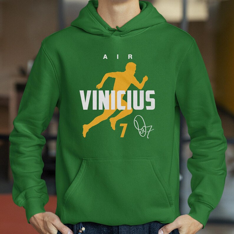 A person wearing a green hoodie with a yellow graphic and text printed on it.