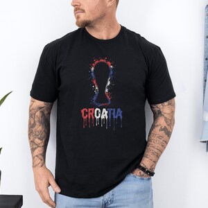 A man wearing a black t-shirt with a graphic design of a trophy and the word "Croatia" printed on it.
