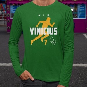 A person wearing a green long-sleeved shirt with a yellow graphic and text printed on it.