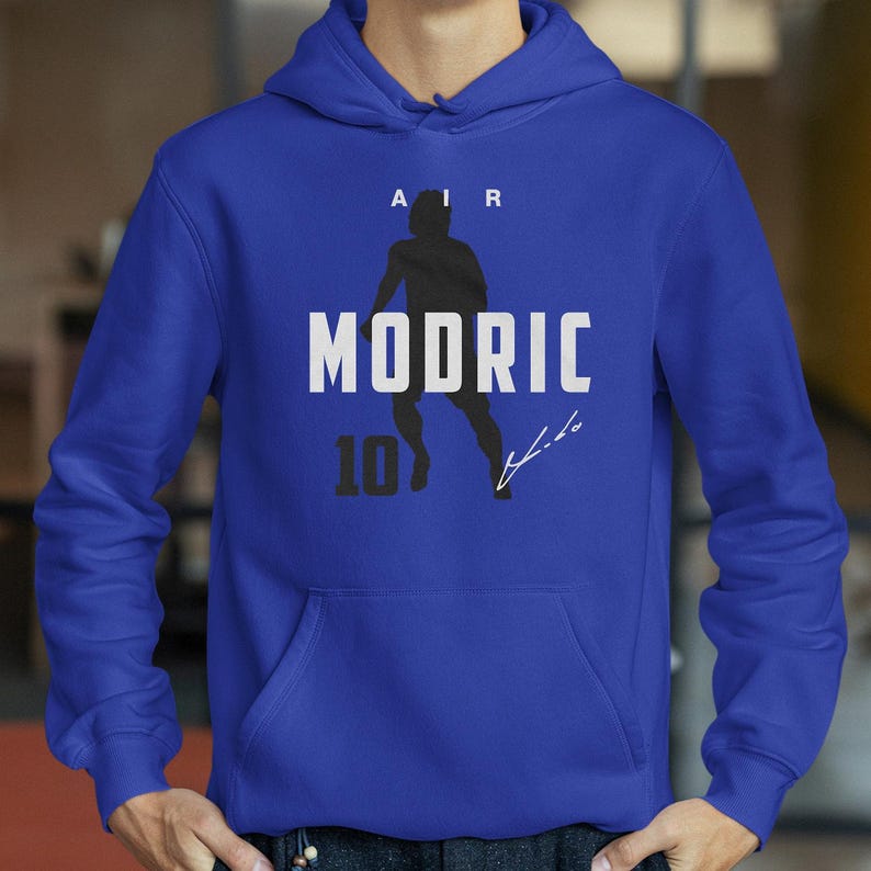 A person wearing a blue hoodie with a graphic design featuring a silhouette of a person and the text "MODRIC 10" printed on it.