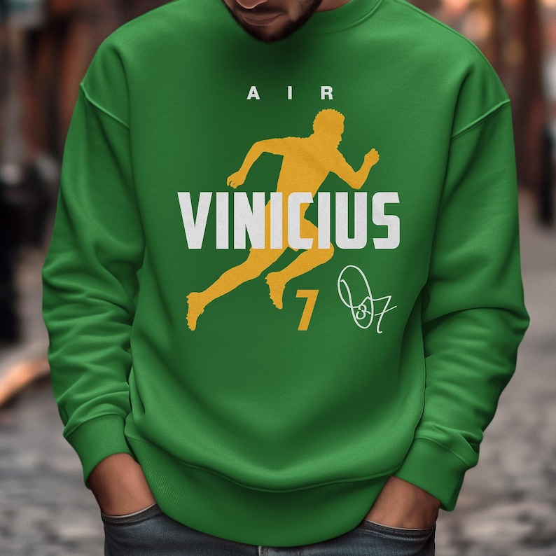 A person wearing a green sweatshirt with a yellow running figure and the text "VINCIUS 7" printed on it.
