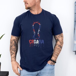 A man wearing a navy blue t-shirt with a graphic design of a key and the word "Croatia" printed on it.