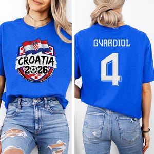 A woman wearing a blue t-shirt with a graphic of the Croatia national flag and the text "CROATIA 2026" printed on it.