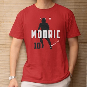 A red t-shirt with a graphic design featuring a silhouette of a person and the text "AIR MODRIC 10" printed on it.