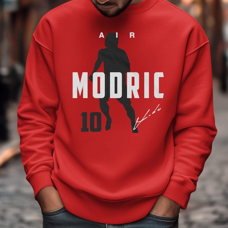 A man wearing a red sweatshirt with the text "AIR MODRIC 10" printed on it.