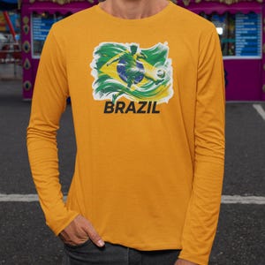 A person wearing a yellow long-sleeved shirt with a graphic of a soccer player and the word "BRAZIL" printed on it.