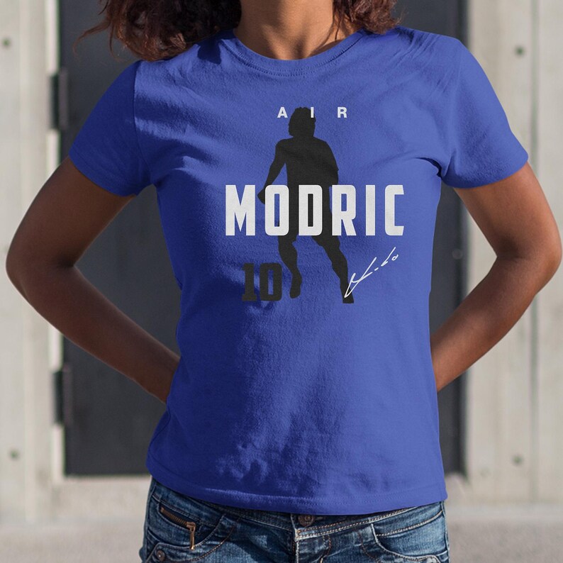 A person wearing a blue t-shirt with a graphic design featuring a silhouette of a person and the text "AIR MODRIC 10" printed on it.