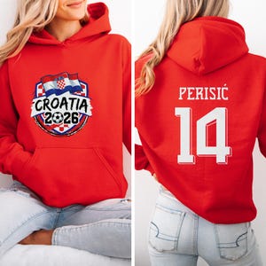 A red hoodie with a graphic of the Croatia national flag and the text "CROATIA 2026" printed on it. The back of the hoodie has the number "14" and the text "PERISIC" printed on it.
