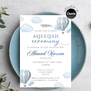 May include: A blue and white Aqeeqah ceremony invitation card. The design includes hot air balloons and clouds. The text announces the event for "Ahmad Hassan" with date and time details. The card is presented on a blue plate.