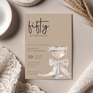 May include: A beige invitation card with the text "fifty & FABULOUS" in black script. The card includes details for Jessica's 50th birthday, a champagne glass with a pearl necklace, and a white bow.