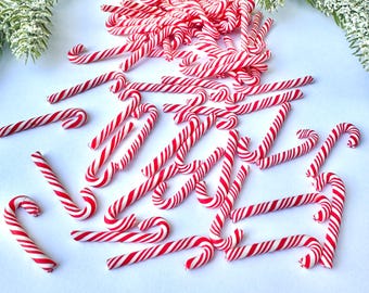 May include: A large pile of red and white candy canes. The candy canes are arranged in a random pattern and are all the same size.