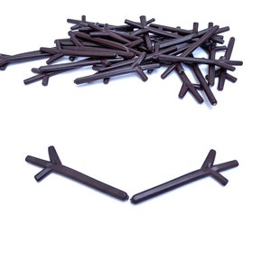 May include: A pile of brown plastic branches for model building. Two branches are separated from the pile and are arranged in a snowman shape.