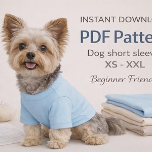May include: A small dog wearing a light blue t-shirt sits in front of sewing supplies and folded fabric. Text on the image reads "INSTANT DOWNLOAD PDF Pattern Dog short sleeves XS - XXL Beginner Friendly."