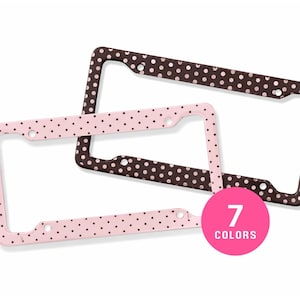 May include: Two rectangular license plate frames featuring a polka dot pattern. One frame is dark brown with light pink dots, and the other is light pink with dark brown dots. A bright pink circular graphic displays the text 7 COLORS.