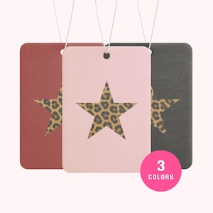 May include: Three rectangular air fresheners in red, pink, and gray, each with a leopard print star cutout. The air fresheners are hanging by white strings. A pink circle with the text "3 COLORS" is in the bottom right corner.
