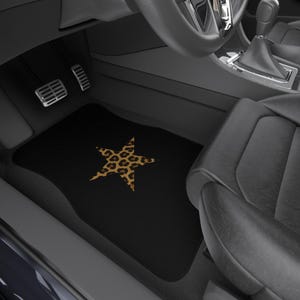 May include: Black car floor mat with a large star design. The star has a leopard print pattern in shades of brown and tan. The mat is rectangular and sits in the driver's side footwell of a car.