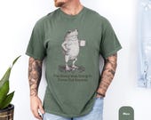 Photo 5 of 8: Funny frog shirt featuring a grumpy frog holding coffee with the phrase The Weird Was Going to Come Out Anyway on a cozy moss green tee, a quirky frog tee and sarcastic funny saying tee for introvert humor, coffee lover, or a gift for him or gift for friend