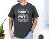 Photo 2 of 8: Charcoal vintage wash shirt modeled by a tattooed man, featuring a bold white novelty quote about the "voices" in his wife's head, cozy unisex humor tee with worn-in texture, a wife voices shirt and funny marriage tee ideal as a gag gift husband or witty relationship present
