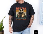 Photo 3 of 8: Model wearing a soft charcoal garment dyed tee designed as a dad tax shirt featuring a retro badger cartoon holding fries and a drink, bold 'Dad Tax' and cheeky 'making sure it's not poison' caption, vintage faded look perfect as a badger dad tee, funny dad shirt, dad humor tee and Father's Day gift