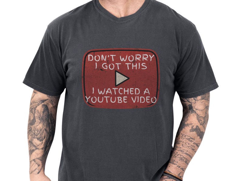 Man modeling a worn-in charcoal Comfort Colors soft cotton tee with a distressed red retro play button graphic that reads a cheeky YouTube DIY meme, cozy casual funny dad shirt idea and handyman gift or Fathers Day tee for him