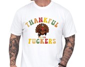 Photo 1 of 8: Casual unisex humor tee on a model featuring a retro turkey illustration and colorful lettering saying Thankful for you fuckers, a cheeky friendsgiving shirt and inappropriate rude shirt idea for funny thanksgiving gifts, soft cotton cozy fit ideal as a gift for friends