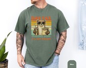 Photo 5 of 8: Soft garment dyed blue jean unisex dad weasel shirt featuring a smiling weasel character holding fries and a soda against retro sunset stripes with a playful Dad Tax joke, a funny dad tee and novelty father gift idea for dad life