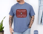Photo 6 of 8: Outdoor lifestyle photo of a man wearing a soft comfort colors shirt with a vintage red retro play button and humorous "I watched a YouTube video" meme slogan, cozy soft cotton tee ideal as a funny dad shirt, handyman gift, Fathers Day tee and gift for him