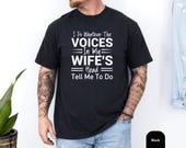 Photo 3 of 8: Funny husband shirt featuring a black unisex humor tee with bold white text that reads “I do whatever the voices in my wife’s head tell me to do,” a witty marriage joke tshirt and playful gag gift husband idea for relaxed everyday wear