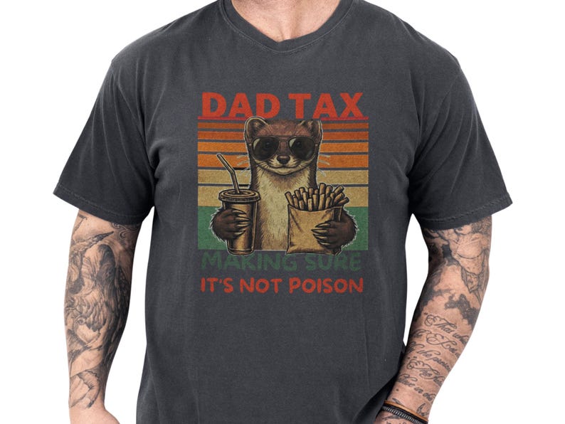 Charcoal garment-dyed unisex dad weasel shirt with a soft worn-in feel, featuring a cheeky weasel in sunglasses holding fries and a soda against vintage sunset stripes, bold DAD TAX humor and "making sure it's not poison" copy, funny dad tee and novelty Father's Day gift idea for proud dads