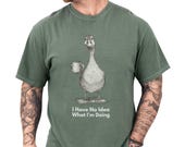 Photo 1 of 8: Casual man models a moss green unisex funny goose shirt featuring a sketched goose holding a coffee mug and the caption I Have No Idea What I'm Doing, a soft, worn-in funny graphic tee with meme t shirt vibes, sarcastic novelty goose t shirt and animal humor shirt, great gift for him or gift for dad, cozy introvert humor apparel
