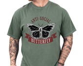 Photo 1 of 8: Vintage style tee with a bold butterfly graphic and “anti-social” lettering on a soft green unisex funny shirt, perfect as a gift for introverts who love edgy humor and a relaxed, quirky look