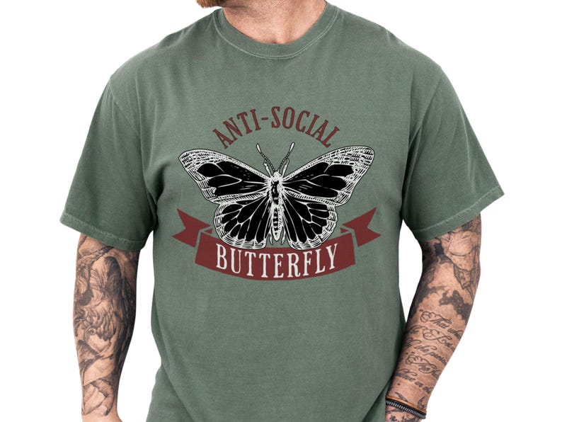 Vintage style tee with a bold butterfly graphic and “anti-social” lettering on a soft green unisex funny shirt, perfect as a gift for introverts who love edgy humor and a relaxed, quirky look
