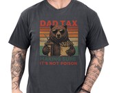 Photo 1 of 8: Casual garment-dyed pepper unisex dad t-shirt showing a retro-striped bear holding fries and a drink with the playful "Dad Tax making sure it's not poison" slogan, a funny dad shirt and dad humor tee with vintage washed look and cozy soft feel, perfect as a fathers day tee or dad birthday gift