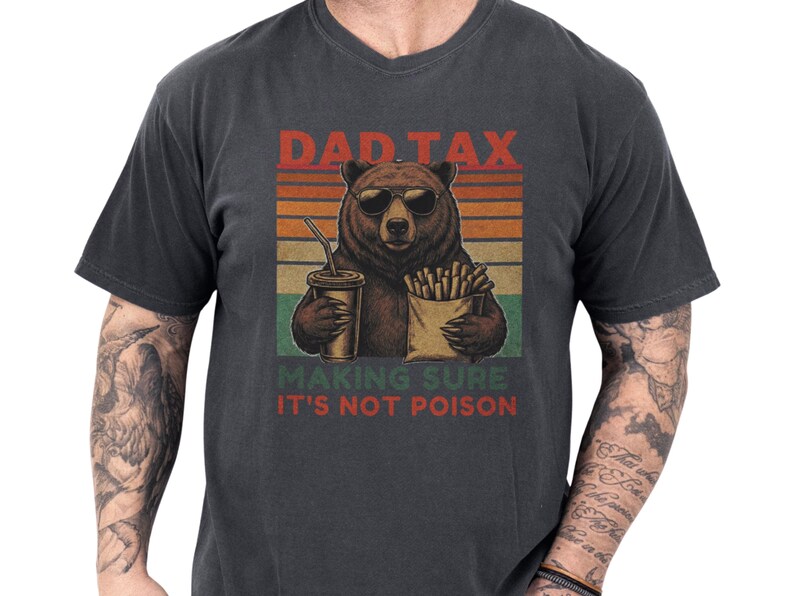 Casual garment-dyed pepper unisex dad t-shirt showing a retro-striped bear holding fries and a drink with the playful "Dad Tax making sure it's not poison" slogan, a funny dad shirt and dad humor tee with vintage washed look and cozy soft feel, perfect as a fathers day tee or dad birthday gift